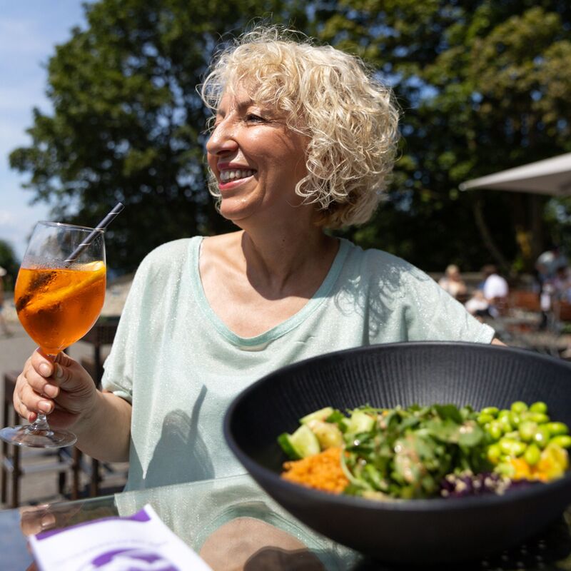 Frau mit Aperol Spritz und Bowl, genießt die Sonne
